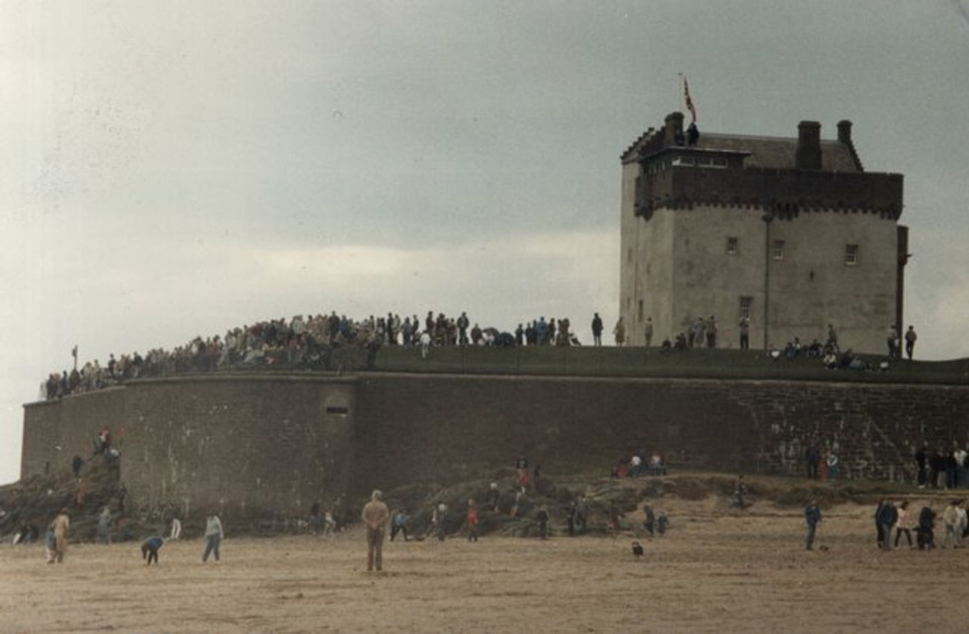Crowds lining the castle walls and the beach below